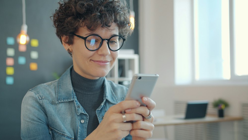 A smiling woman reading a text on her phone